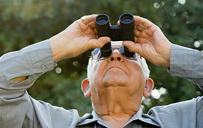 Man with glasses looking through binoculars